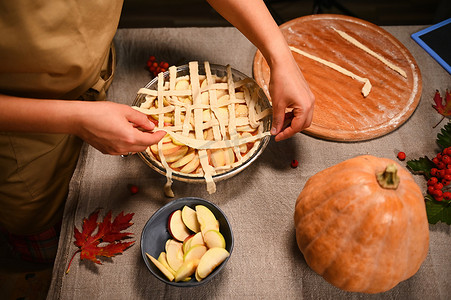 家庭主妇用松脆的糕点格子装饰节日自制南瓜苹果派的顶视图。