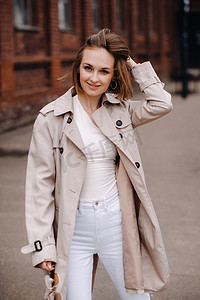 一个穿着灰色外套的快乐时尚女孩在城市里散步