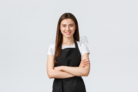 穿着黑色围裙、开朗微笑的女咖啡师双臂交叉在胸前，看起来准备就绪，充满自信。