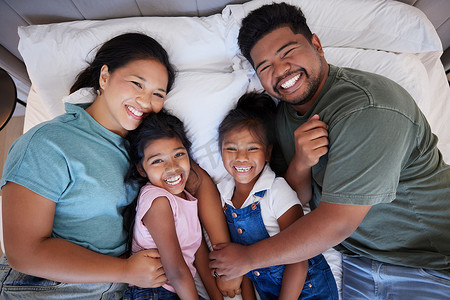 一个幸福的黑人家庭在床上，爸爸妈妈充满爱地抱着孩子。