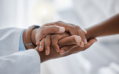 医生和患者手牵着手，分享癌症诊断的坏消息，提供支持、信任和医院护理。