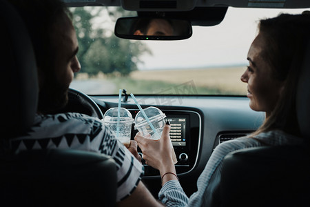 回眸中年夫妇坐在车内喝咖啡，男女一起享受公路旅行