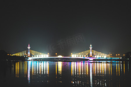泰国夜景摄影照片_泰国城市夜景与黄昏时分河边摩天大楼和桥梁的美丽倒影。