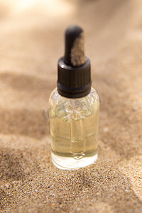 玻璃瓶中的化妆品血清，沙子中有吸管