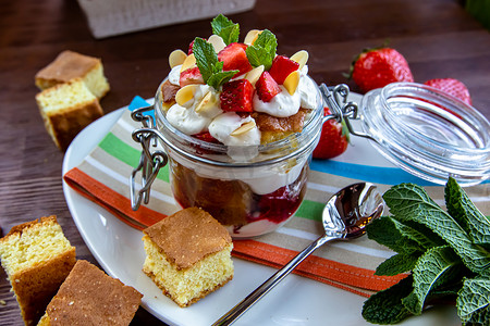 巧克力海绵蛋糕、生奶油或乳清干酪和新鲜草莓放在玻璃碗中的分层甜点。