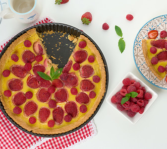 白桌上的圆形乳蛋饼，上面有红草莓和覆盆子，顶视图