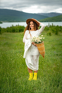 一名身穿白色连衣裙、棕色帽子的中年妇女抱着一名身穿白色连衣裙、棕色帽子的中年妇女，她手里拿着一个篮子，里面放着一大束雏菊。她手里拿着一大束雏菊。