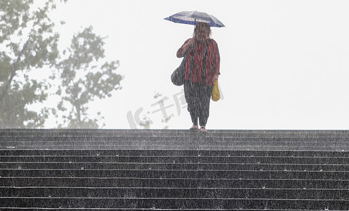 雨中街道摄影照片_雨中伞下快乐微笑的女人的肖像