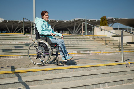 坐在轮椅上的白人妇女如果没有坡道就无法下楼梯。