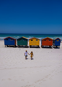一对男女参观 Muizenberg 的海滩，开普敦 Muizenberg 海滩的彩色海滨别墅，海滩小屋，Muizenberg，开普敦，福尔斯湾，南非