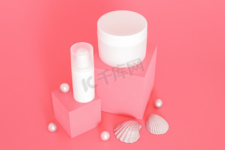 本子样机摄影照片_白色无品牌化妆品霜罐群站在粉红色的讲台上，上面放着银球和贝壳。