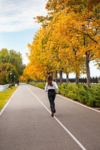 年轻的成年女性在秋天的树林中奔跑。