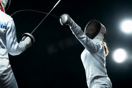 年轻的击剑运动员戴着面具和白色击剑服装。