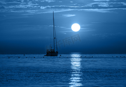 发光的海摄影照片_美丽的夜海、游艇和满月。