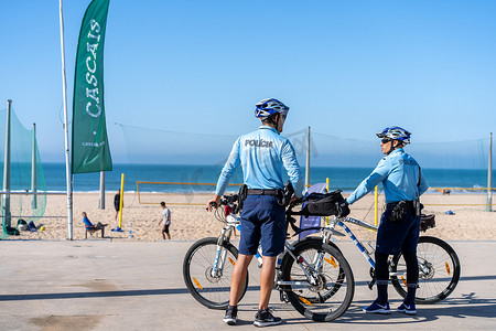 葡萄牙，卡卡维洛斯，2022 年 4 月，两名警察骑自行车在海滨长廊巡逻。