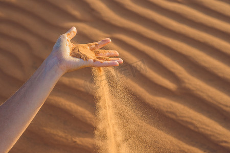 沙漠中，沙子从女人的手指间滑落