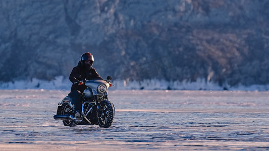 骑自行车的人骑着摩托车哈雷戴维森在结冰的湖面上。 