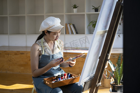微笑的年轻女子在艺术工作室用水彩画画。