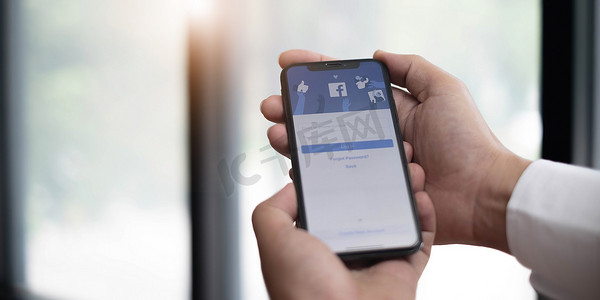 泰国清迈，2022 年 7 月 13 日：一名女子手持 iPhone X，屏幕上显示社交互联网服务 Facebook。
