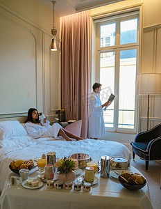 早晨在巴黎的床上醒来，早餐咖啡和报纸，男人和女人 honemoon