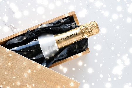 活动礼盒摄影照片_圣诞假期香槟瓶、礼盒和大理石背景上闪亮的雪
