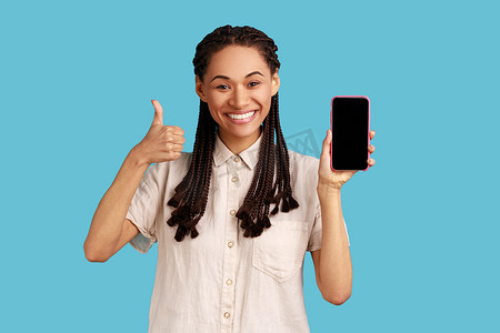 女人幸福地微笑着，指着手机的空白屏幕，为新产品做广告，竖起大拇指。