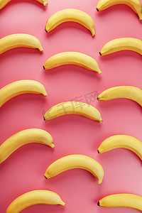 黄色几何创意摄影照片_粉红色背景上香蕉的几何图案。