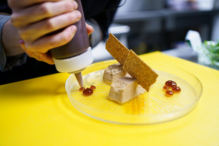 油煎摄影照片_作物厨师在餐厅用松脆的油煎面包块电镀鹅肝酱