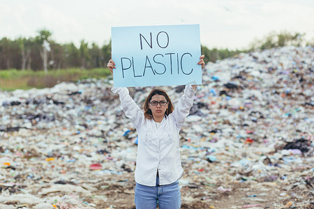 女志愿者在垃圾填埋场举着无塑料海报，积极分子与环境污染作斗争