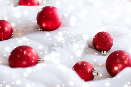 蓬松毛皮上的红色圣诞小玩意，雪花闪闪发光，奢华的冬季假期设计背景
