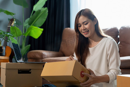 运送给客户的小型商业包裹，年轻的亚洲女性收到网上购物包裹开箱并通过信用卡购买物品，在线营销采购订单包装产品