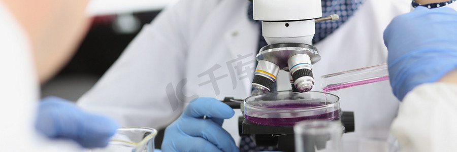 女科学家在实验室显微镜下探索紫色样品