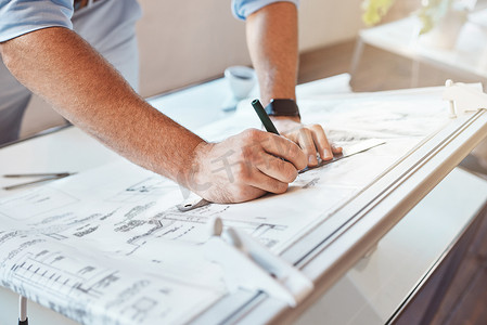 男性建筑师在办公桌上手绘建筑项目或施工计划。