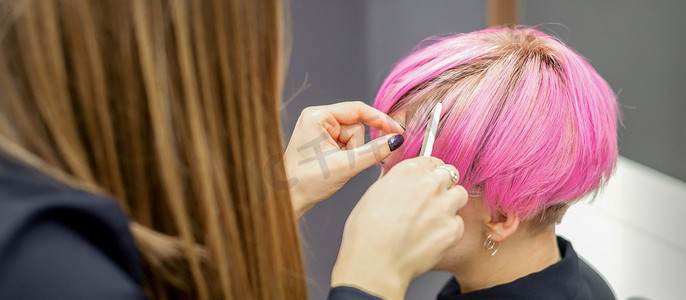 美发师为一名年轻女子染成粉色短发，准备在美容院进行手术。