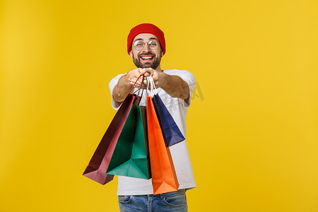 免费场摄影照片_留着胡子的男人，提着购物袋，在黄色的免费场地上感到快乐