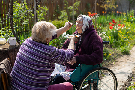 中老年声乐摄影照片_坐在轮椅上的八十多岁老妇人在家中被喂食