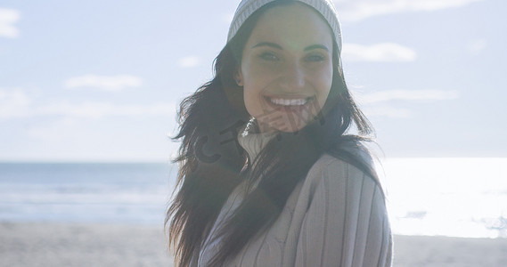 穿着秋装的女孩在海滩上微笑