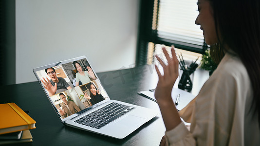 年轻女商人在网上与同事聊天，在家办公室通过笔记本电脑进行视频通话