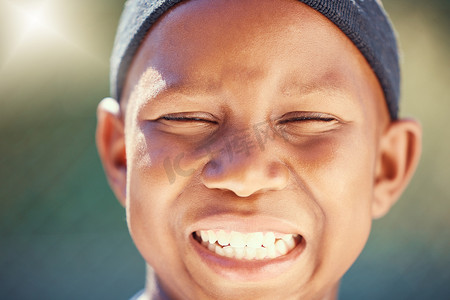 孩子们，脸上和牙齿上有一个黑人男孩，外面带着灿烂的笑容，闭着眼睛。