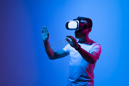 留着胡子、雄心勃勃的现代男性戴着 VR 眼镜工作，同时用手指指着虚拟现实中的主题。