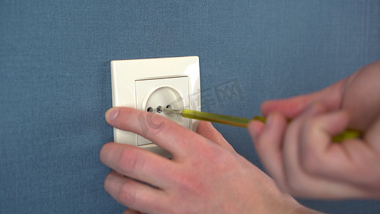 电工用专用螺丝刀将插座安装在墙上。