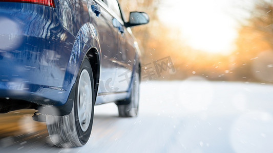 蓝色汽车在冬季雪路上快速行驶。