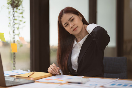 亚洲女商人的形象缓解了因久坐工作而造成的颈部疼痛。