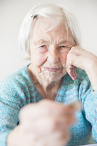 悲伤的老妇人坐在家里的桌子旁，悲惨地看着手里只剩下养老金的硬币。