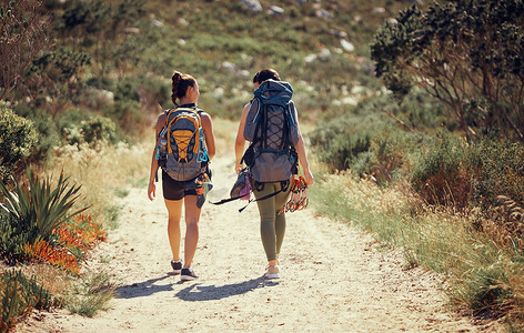 健身和锻炼的朋友在山间尘土小路上徒步旅行或在大自然中散步。