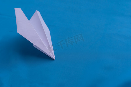 白色的纸飞机摄影照片_蓝色背景上的纸飞机