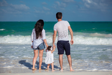 带着小孩的父母在海滩上散步，欣赏地平线。