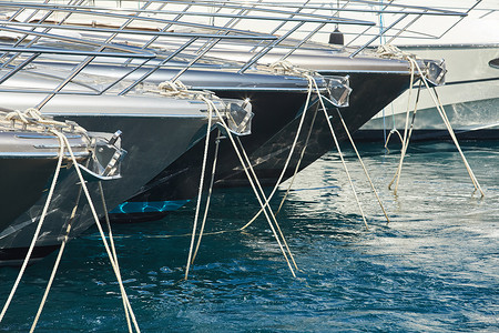 进入水里摄影照片_摩纳哥、蒙特卡洛，阳光明媚的日子里，很多摩托艇停泊在港口，系泊绳索进入蔚蓝的海水，一排摩托艇的船头，船栏杆