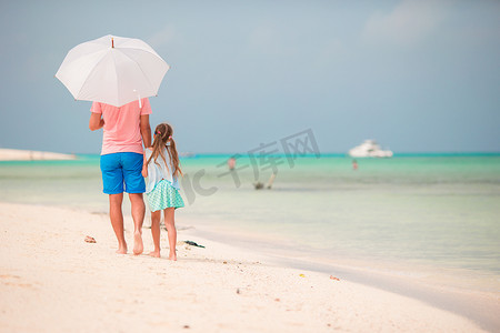 海滩上带伞的家庭后视图