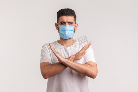 戴防护面具的男子双臂交叉站立，示意停止，警告冠状病毒流行